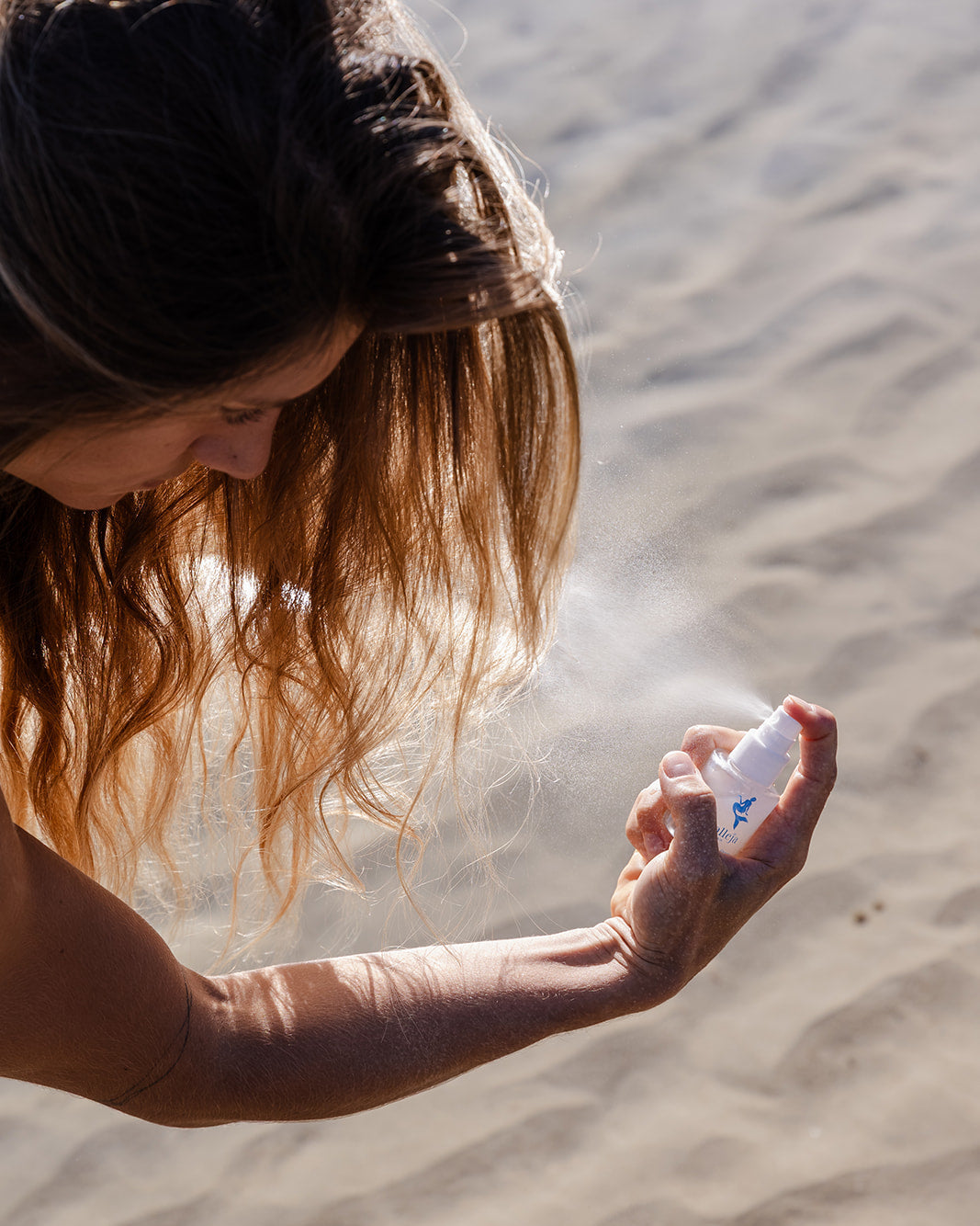 Person applying hair spray in a desert setting